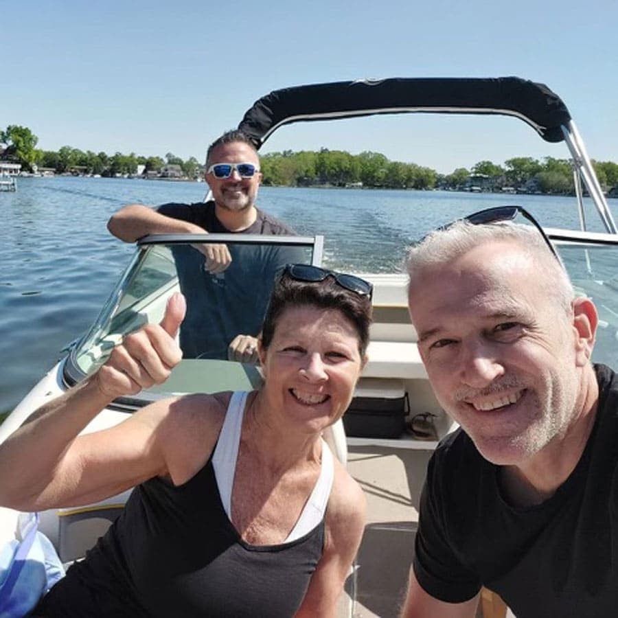Three people enjoying a sunny day on a boat by the water.