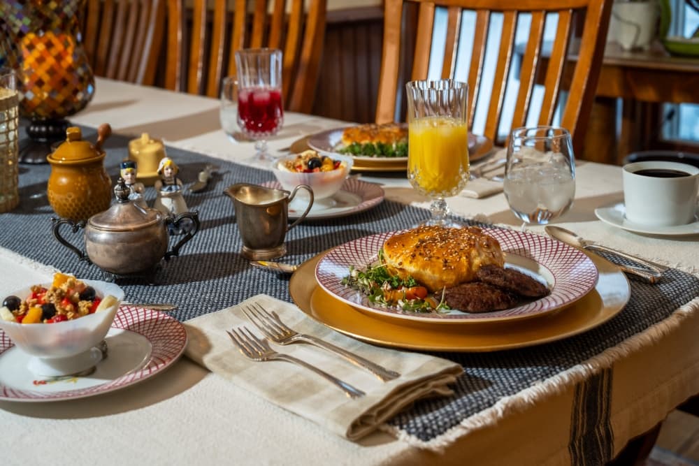 A beautifully arranged breakfast table featuring a variety of dishes, drinks, and elegant tableware.