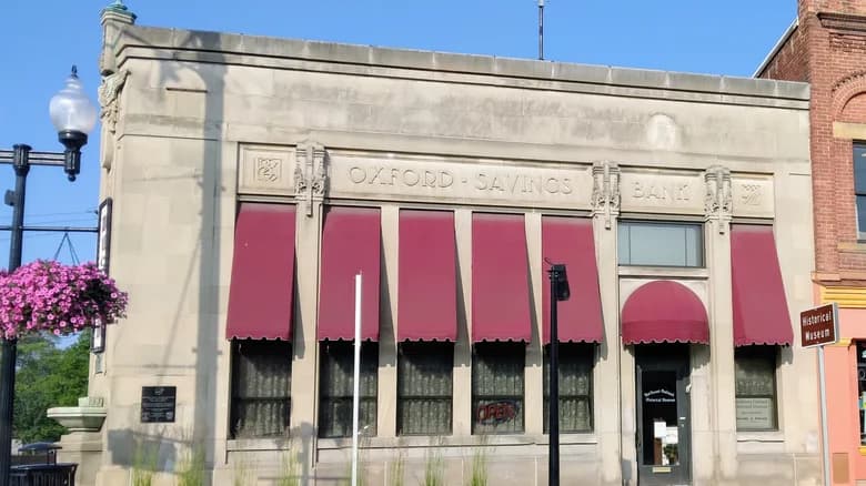 Historic building of Oxford Savings Bank with burgundy awnings.