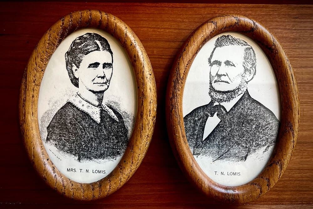 Two framed portraits of a woman labeled "Mrs. T. N. Lom is" and a man labeled "T. N. Lom is."
