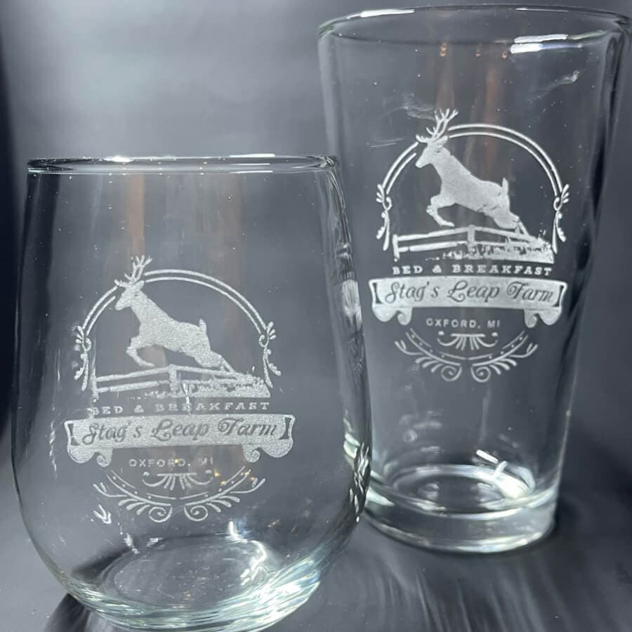Two engraved glassware pieces featuring the logo of "Stag's Leap Farm" bed and breakfast in Oxford, MI.
