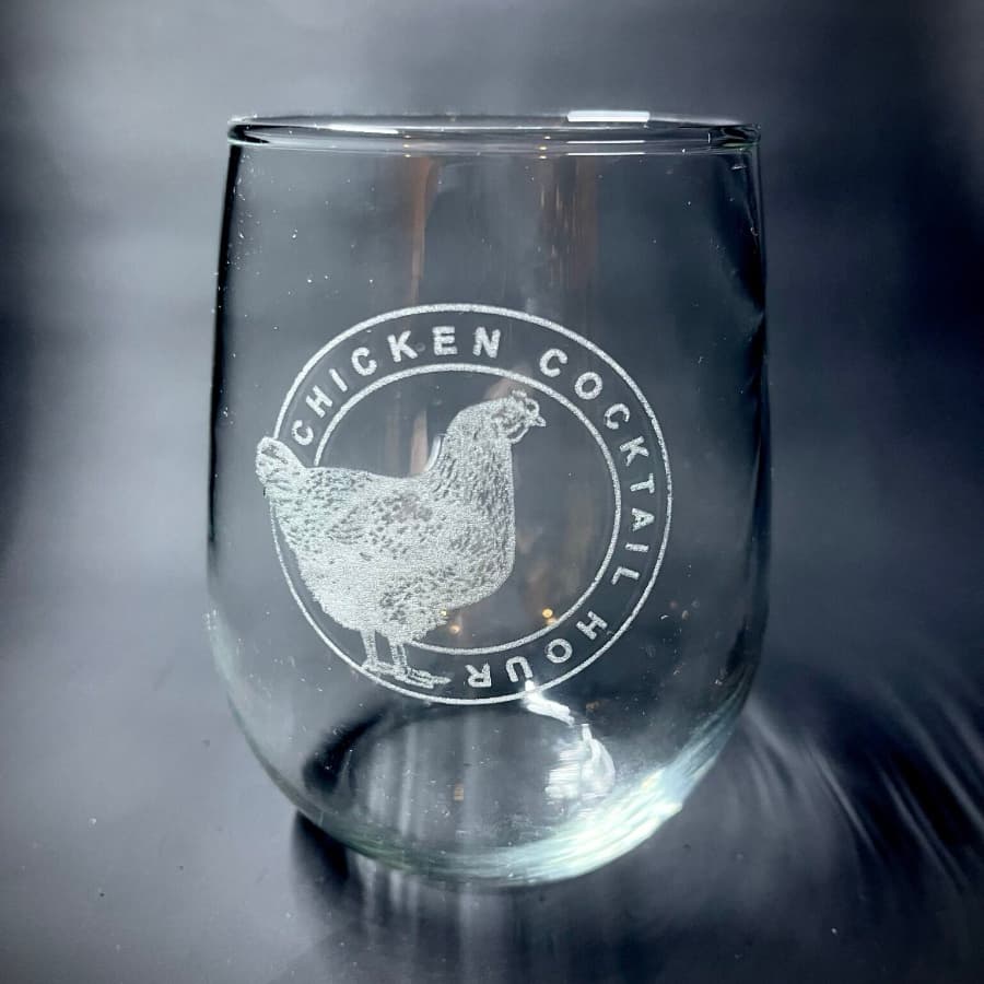 A clear glass with an etched design featuring a chicken and the words "Chicken Cocktail Hour."
