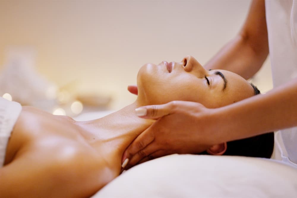 A person receives a neck massage in a serene spa setting.