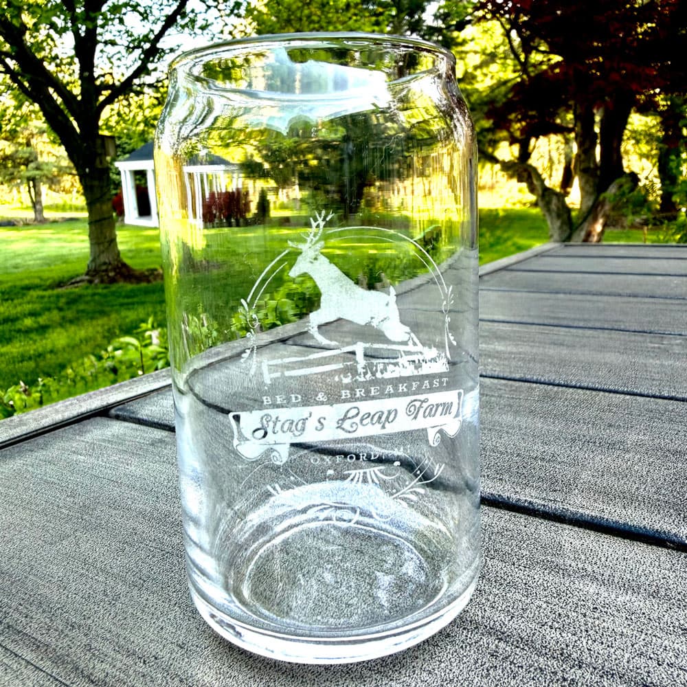 A clear glass jar featuring an engraved design of a stag and text that reads "Stag's Leap Farm Bed & Breakfast."